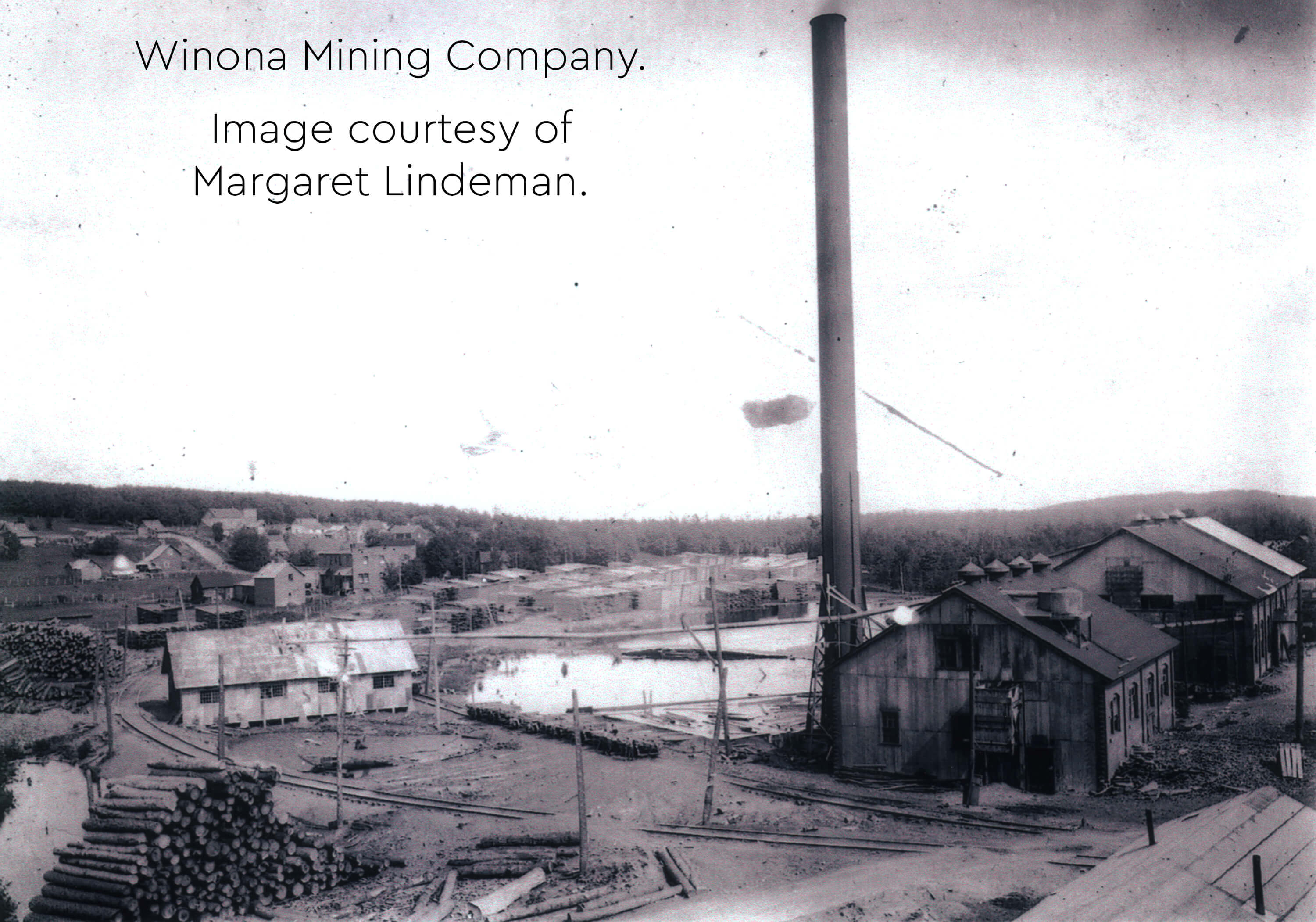 Historic image of the Winona Mining Company with industrial buildings and a smokestack.